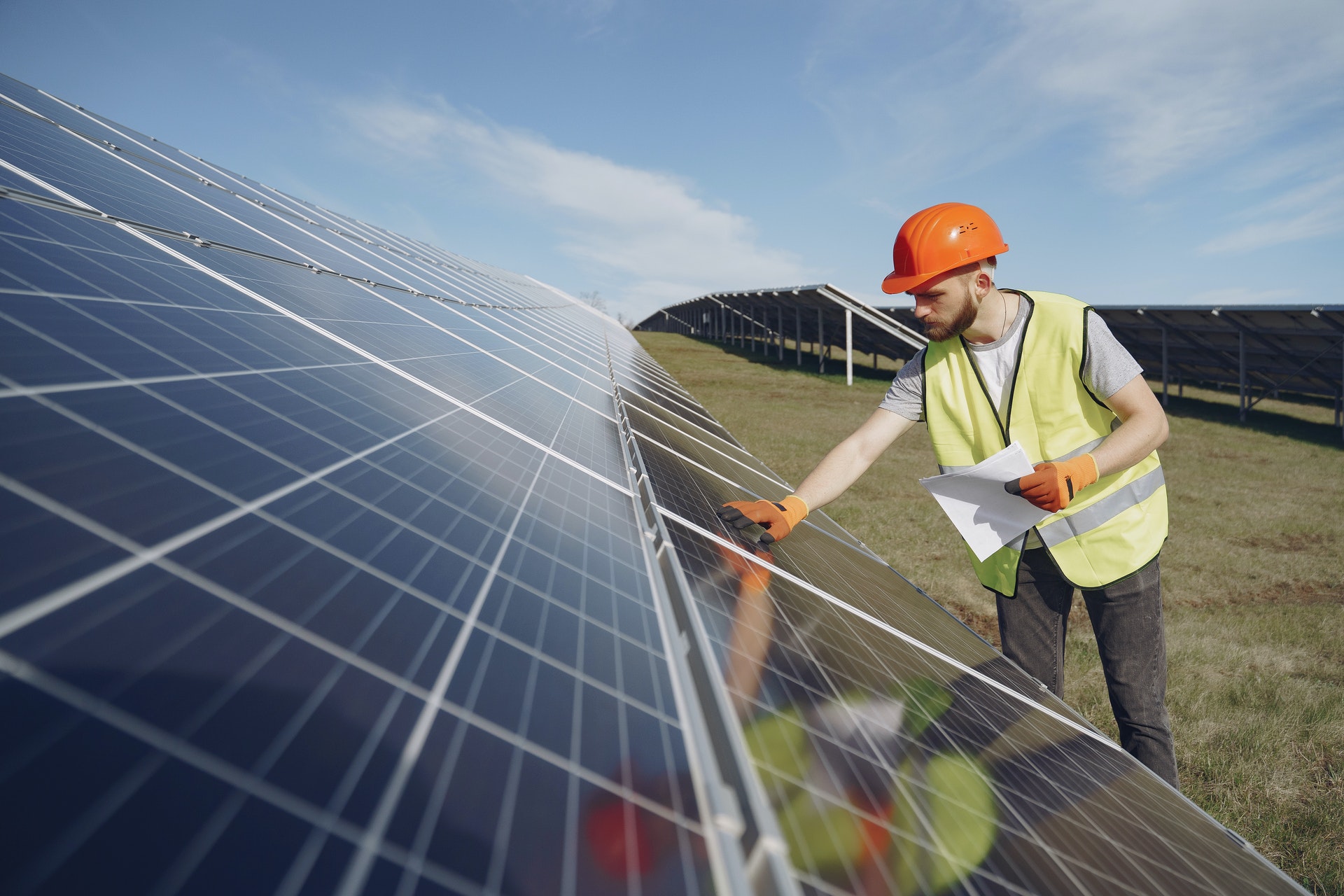 Solar panels in a field getting checked by a construction worker