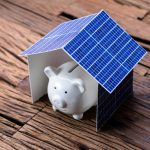 Piggy bank under a solar panel house