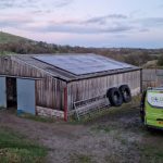 go green van outside a barn with solar panels on